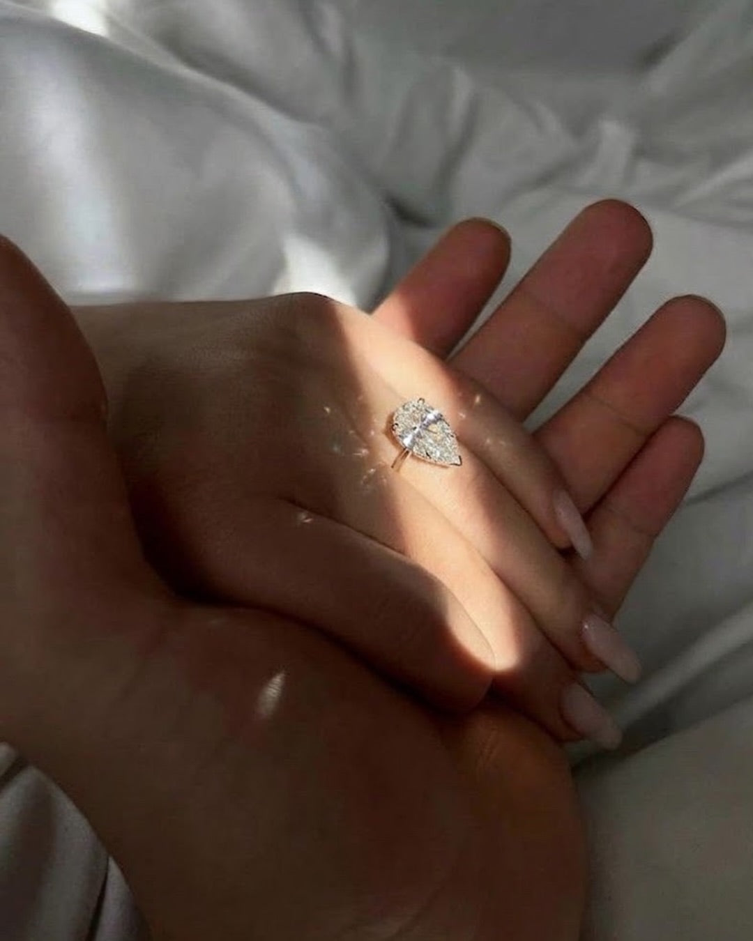 Hand wearing a diamond ring with a white background